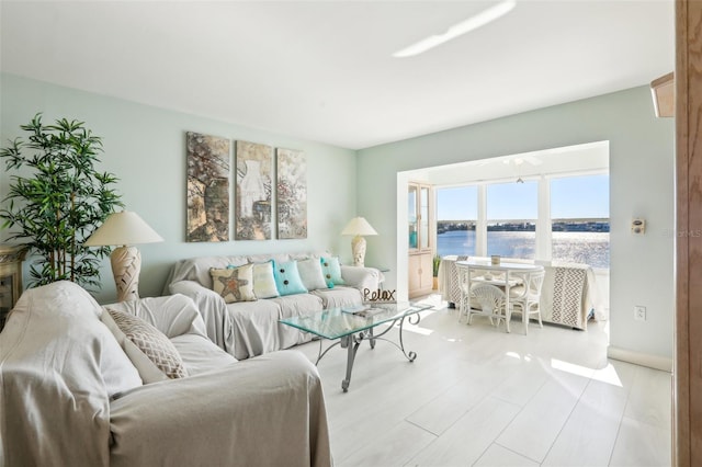 living room with a water view, light wood finished floors, and baseboards