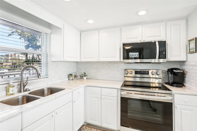 kitchen featuring appliances with stainless steel finishes, light countertops, white cabinets, and a sink