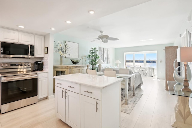 kitchen with recessed lighting, white cabinetry, appliances with stainless steel finishes, light wood-type flooring, and tasteful backsplash