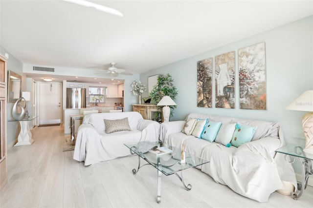 living area featuring ceiling fan, light wood-type flooring, and visible vents