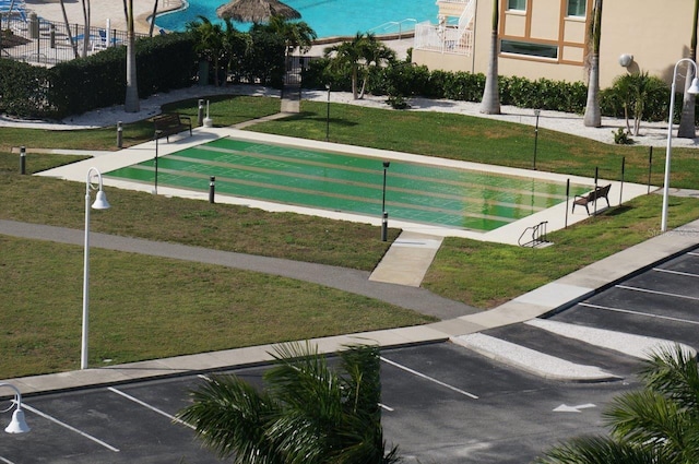 view of community with shuffleboard and a lawn