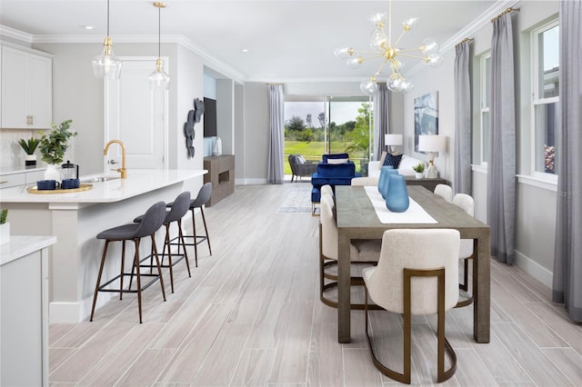 dining area with crown molding, sink, a notable chandelier, and light wood-type flooring