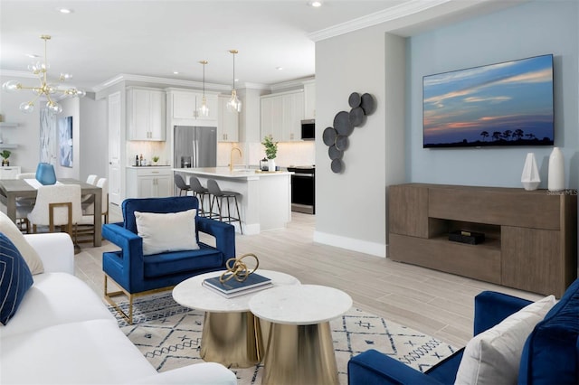 living room featuring sink, an inviting chandelier, light hardwood / wood-style floors, and ornamental molding