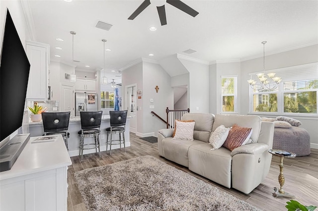 living room featuring ceiling fan with notable chandelier, light hardwood / wood-style flooring, and crown molding