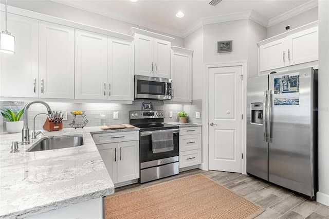 kitchen featuring appliances with stainless steel finishes, white cabinetry, hanging light fixtures, and sink