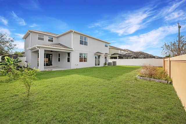 rear view of property featuring a lawn, ceiling fan, central AC unit, and a patio area