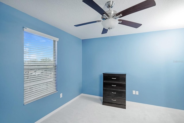 unfurnished bedroom featuring carpet flooring, a textured ceiling, and ceiling fan