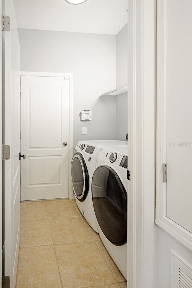 laundry room featuring washing machine and dryer and light tile patterned floors