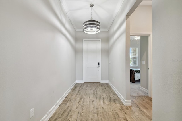 hallway with crown molding, a notable chandelier, and light wood-type flooring