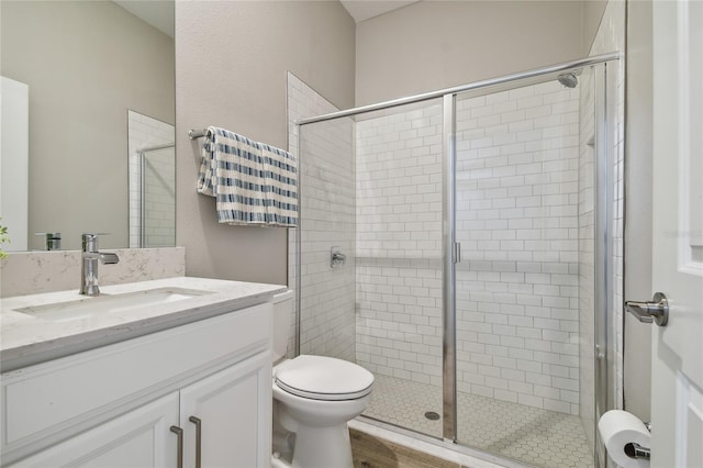 bathroom featuring wood-type flooring, vanity, toilet, and a shower with door