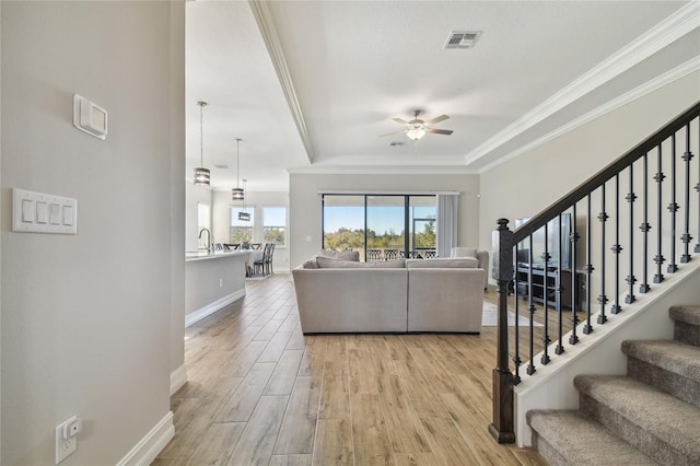 living room with light wood-type flooring, ceiling fan, crown molding, and sink