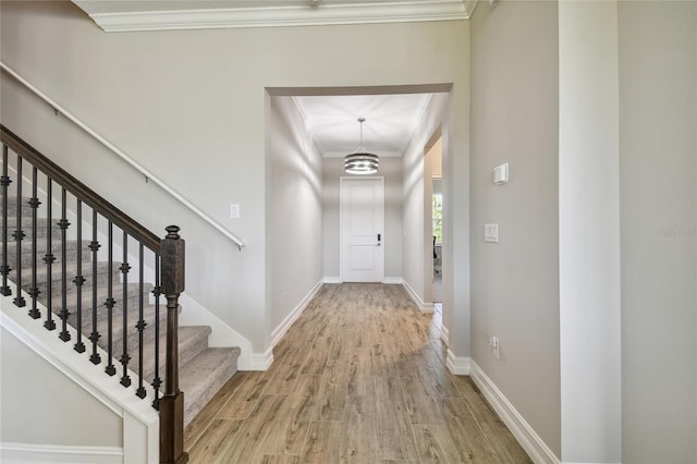 entrance foyer featuring wood-type flooring, ornamental molding, and a chandelier