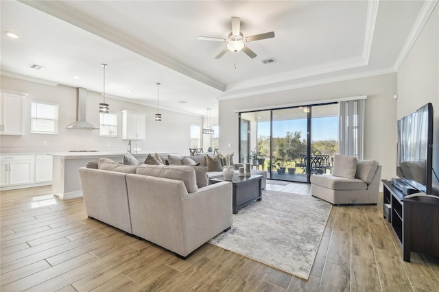 living room featuring ceiling fan, ornamental molding, and light wood-type flooring