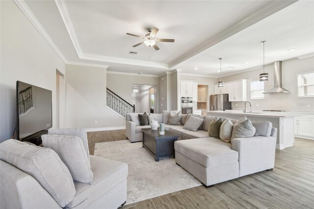 living room with ceiling fan, light hardwood / wood-style flooring, sink, and ornamental molding