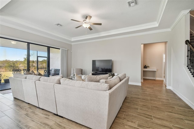 living room featuring a raised ceiling, ceiling fan, hardwood / wood-style floors, and ornamental molding