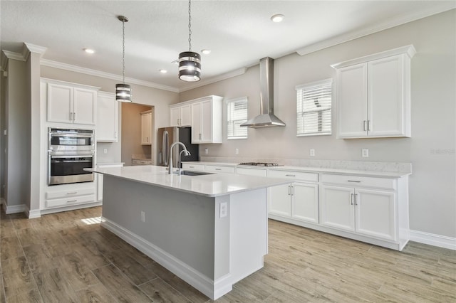 kitchen with pendant lighting, light hardwood / wood-style flooring, wall chimney exhaust hood, white cabinetry, and stainless steel appliances