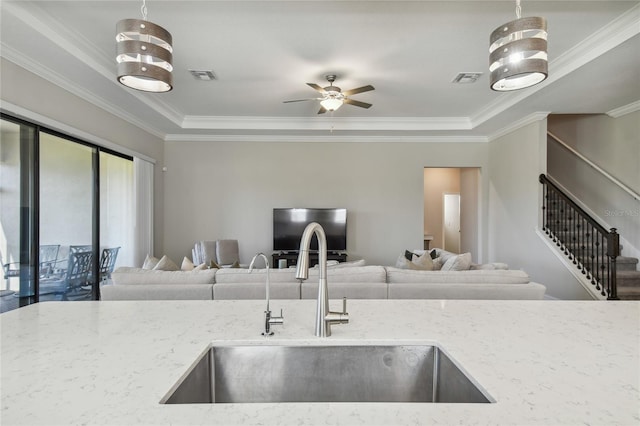 kitchen with crown molding, light stone countertops, sink, and hanging light fixtures