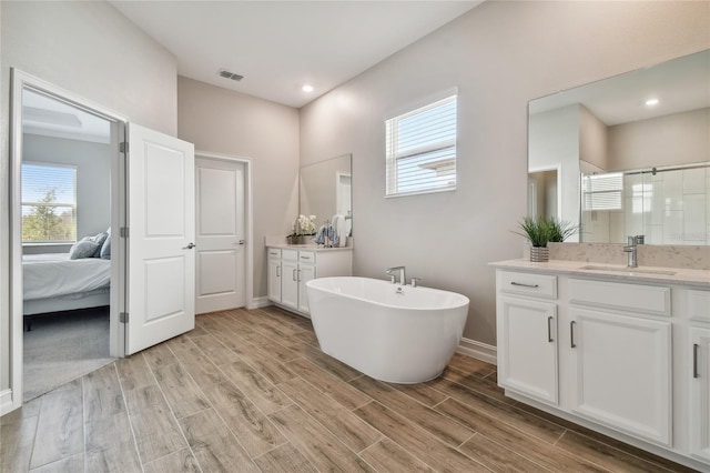 bathroom with hardwood / wood-style flooring, vanity, and plus walk in shower