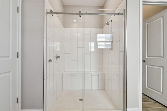 bathroom with a shower with shower door and wood-type flooring