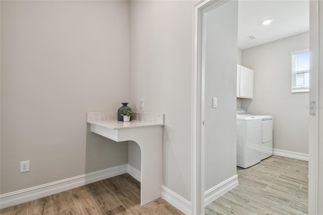 laundry area featuring washer and dryer, cabinets, and light wood-type flooring