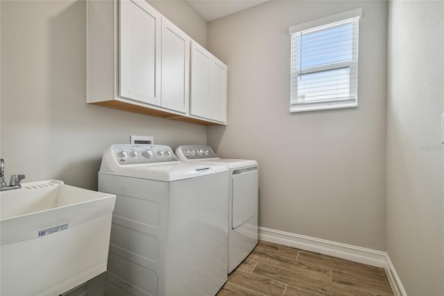 washroom featuring cabinets, dark hardwood / wood-style floors, washing machine and clothes dryer, and sink