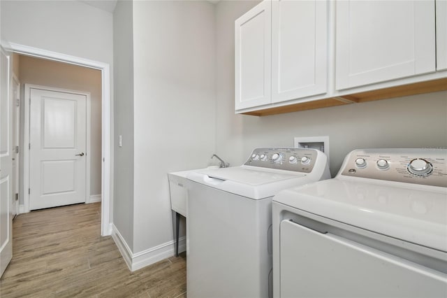 washroom featuring cabinets, light hardwood / wood-style flooring, and washer and clothes dryer