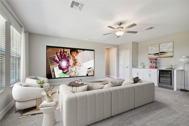 carpeted cinema with ceiling fan, beverage cooler, and indoor wet bar