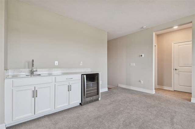 kitchen featuring light carpet, white cabinetry, and wine cooler