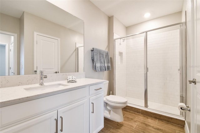 bathroom with hardwood / wood-style floors, vanity, toilet, and a shower with door