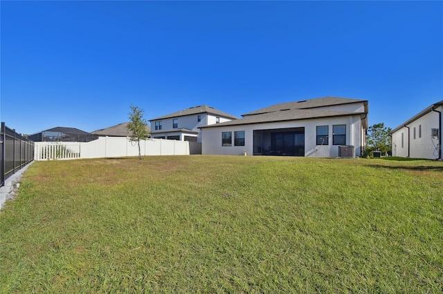 back of property with a lawn and central AC