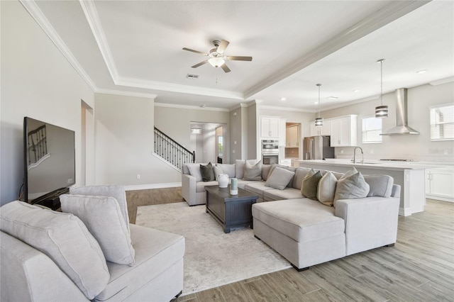 21291 Snowy Orchid Ter, Land O Lakes, FL 34637 - living area featuring light wood-style floors, a ceiling fan, a tray ceiling, stairs, and crown molding