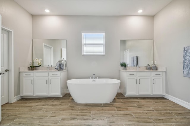 21291 Snowy Orchid Ter, Land O Lakes, FL 34637 - full bath featuring wood finish floors, a soaking tub, two vanities, baseboards, and recessed lighting