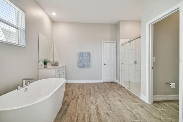 21291 Snowy Orchid Ter, Land O Lakes, FL 34637 - bathroom with wood tiled floors, vanity, a stall shower, a freestanding tub, and recessed lighting