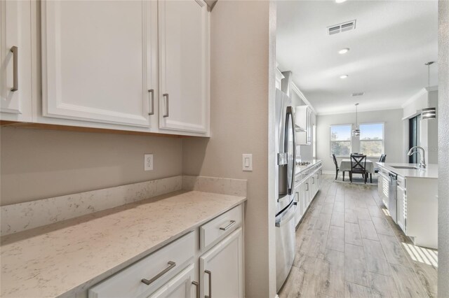 21291 Snowy Orchid Ter, Land O Lakes, FL 34637 - kitchen featuring a sink, white cabinetry, appliances with stainless steel finishes, hanging light fixtures, and light stone countertops