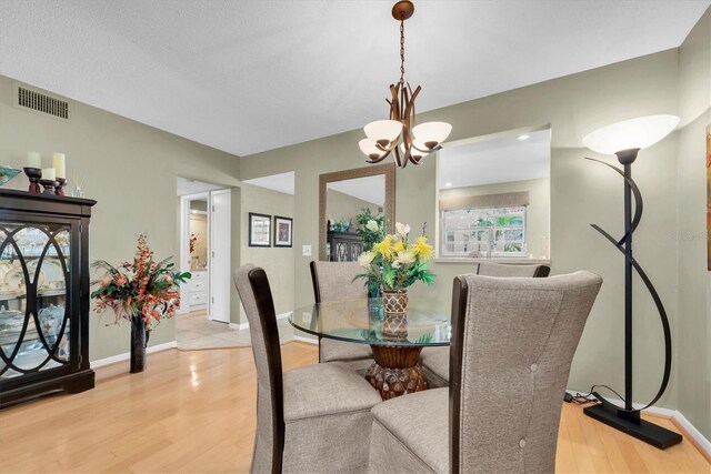 dining room with light hardwood / wood-style floors and a notable chandelier