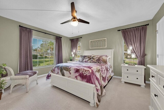 bedroom with ceiling fan, light colored carpet, and a textured ceiling