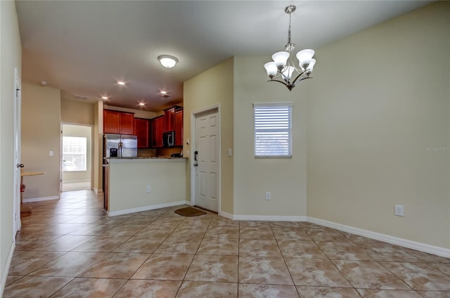 interior space featuring appliances with stainless steel finishes, a notable chandelier, and light tile patterned flooring