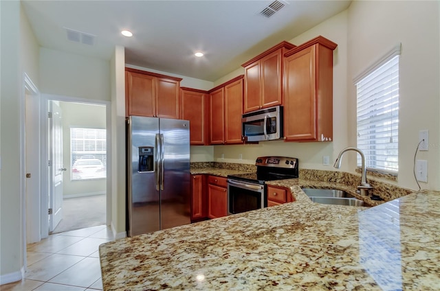 kitchen featuring light stone counters, sink, light tile patterned floors, and stainless steel appliances