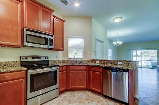 kitchen with a healthy amount of sunlight, sink, stainless steel appliances, and an inviting chandelier