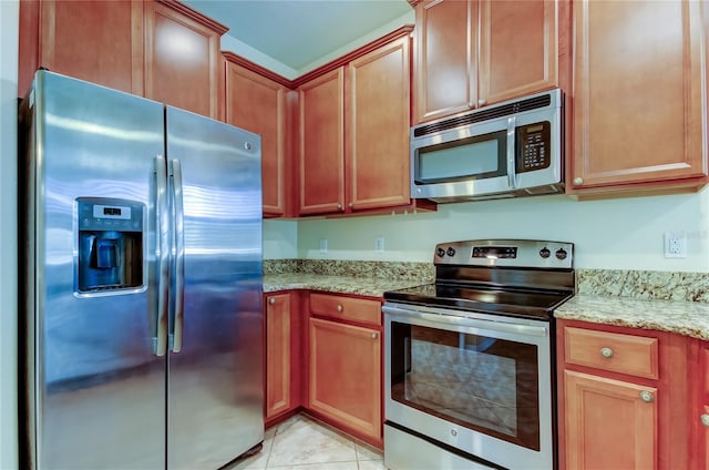 kitchen with light stone countertops, light tile patterned flooring, and appliances with stainless steel finishes