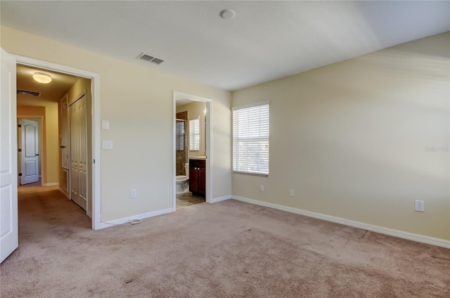 unfurnished bedroom with light carpet and connected bathroom