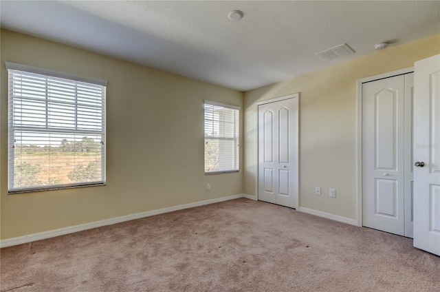 unfurnished bedroom with light carpet and two closets