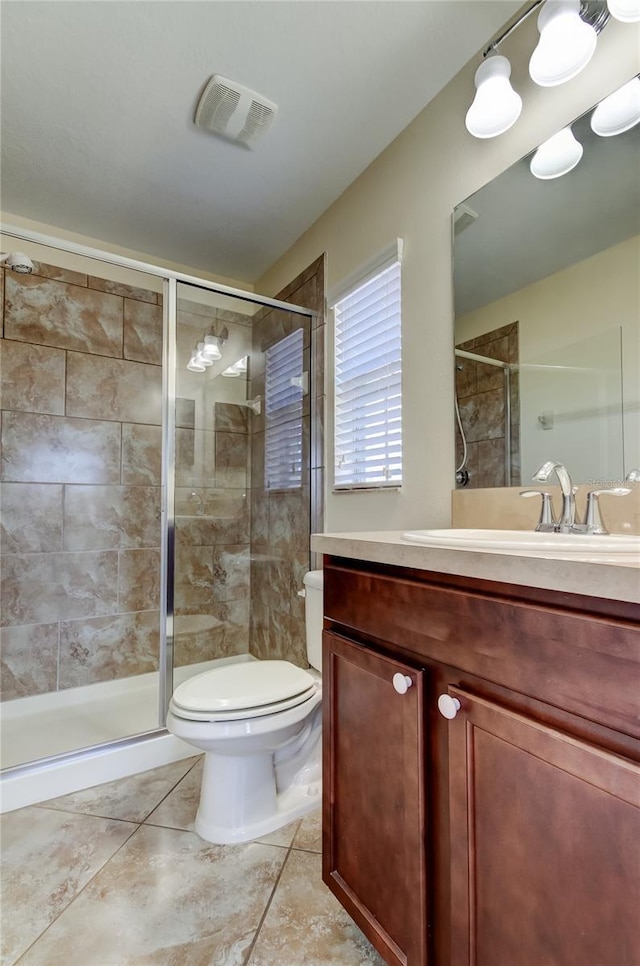 bathroom with tile patterned flooring, vanity, a shower with door, and toilet