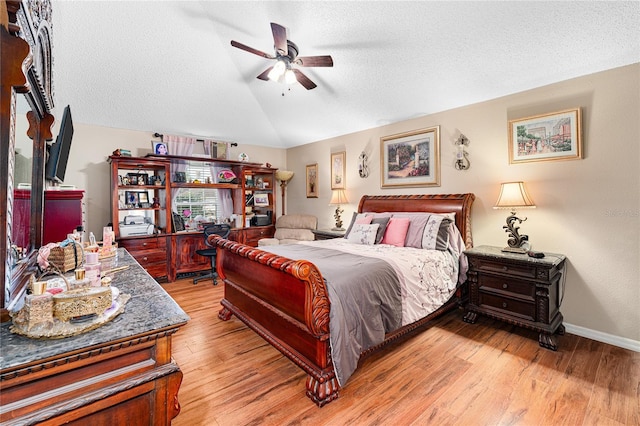 bedroom with ceiling fan, light wood-type flooring, a textured ceiling, and vaulted ceiling