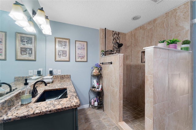 bathroom featuring a tile shower, vanity, and a textured ceiling