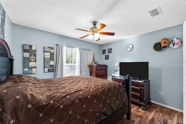 bedroom with ceiling fan, wood-type flooring, and a textured ceiling