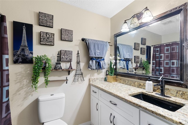 bathroom with vanity, a textured ceiling, and toilet