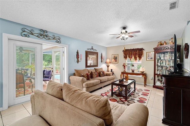 living room featuring ceiling fan, light tile patterned floors, and a textured ceiling