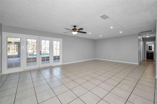 empty room featuring ceiling fan, light tile patterned flooring, and a textured ceiling