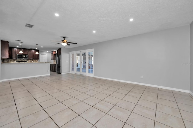 unfurnished living room featuring ceiling fan, light tile patterned flooring, a textured ceiling, and french doors